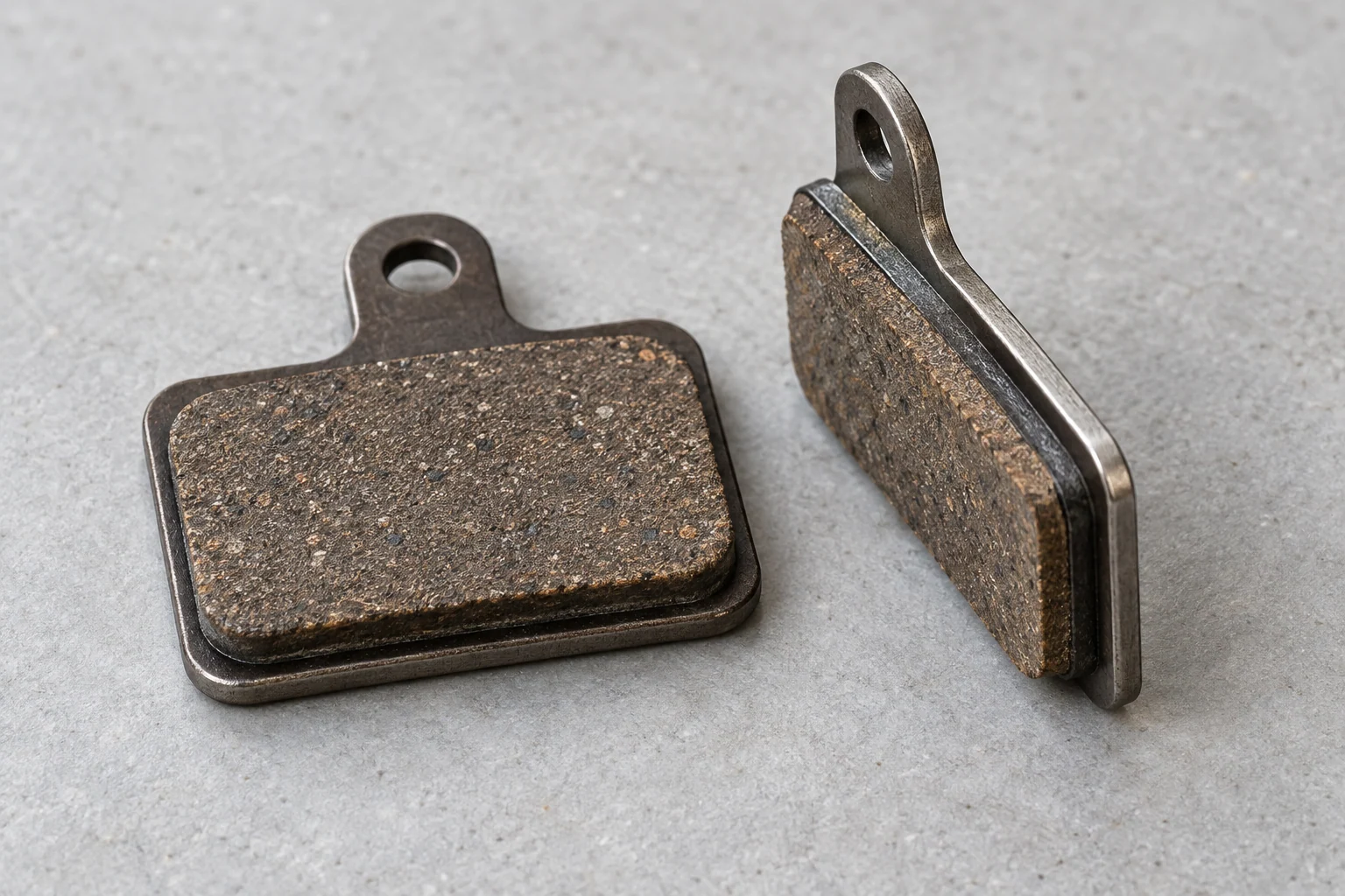 Dos pastillas de freno de disco, una de frente y otra de canto para distinguir material de fricción y placa metálica